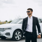 handsome business man by the white car